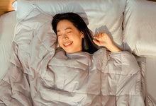 Happy woman sleeping under Sonno Huggy Blanket