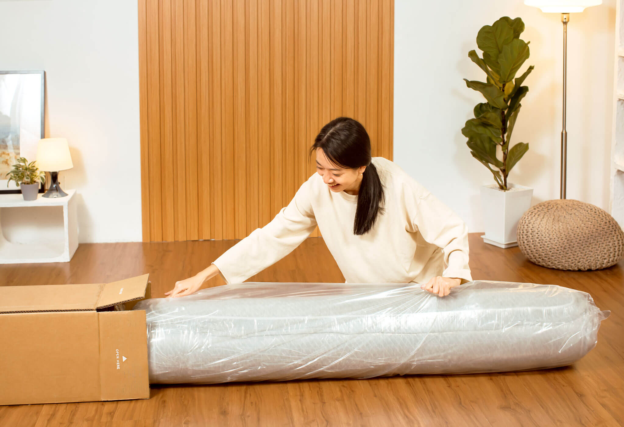 Woman unboxing Sonno Lite mattress in a Japandi bedroom